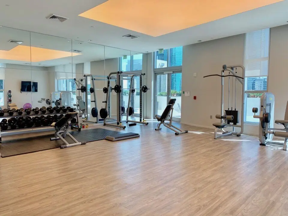 Modern gym at 1100 Millecento featuring exercise equipment and large mirrors.