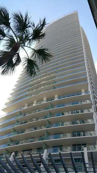 The sleek facade of 1100 Millecento featuring glass balconies under a clear Miami sky.