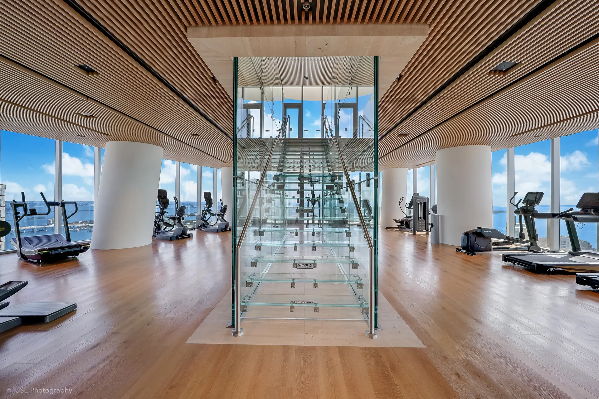 Aston Martin Residences gym with ocean views and glass staircase.