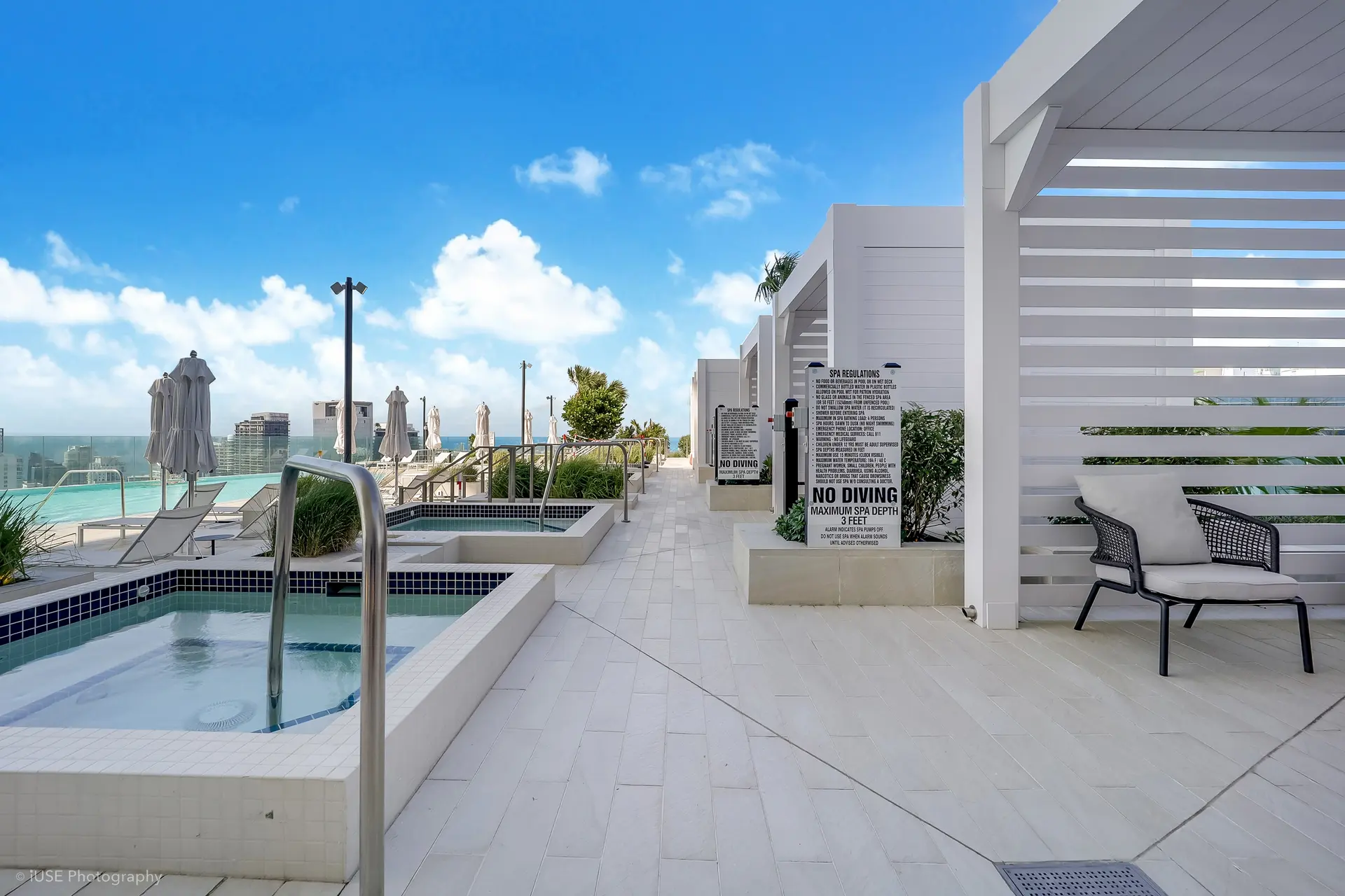 Aston Martin Residences poolside seating and spa area with Miami skyline view.