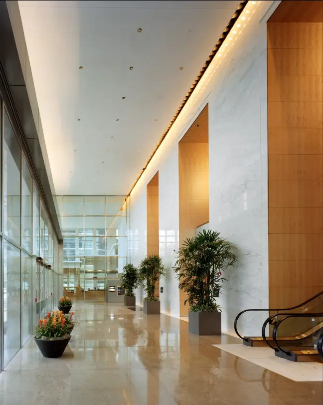 Modern light-filled lobby with escalator and plants at Brickell Arch.