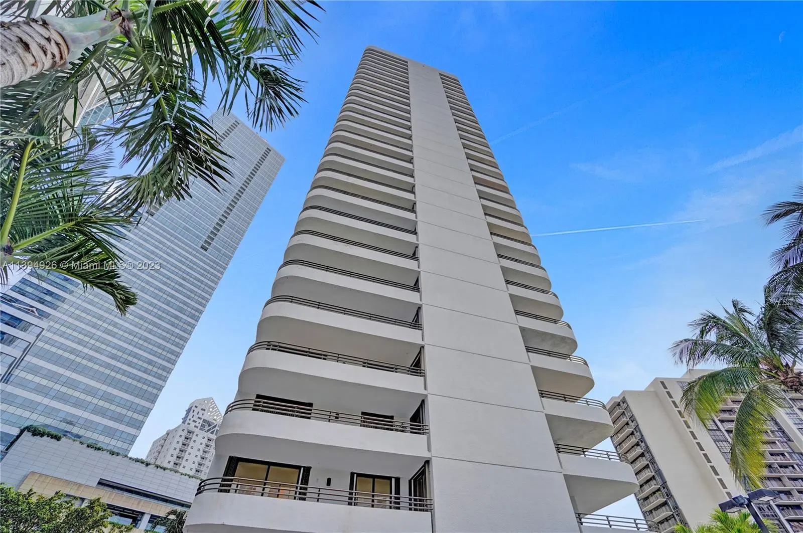 Brickell East modern condo towers with palm trees and blue sky in Miami.