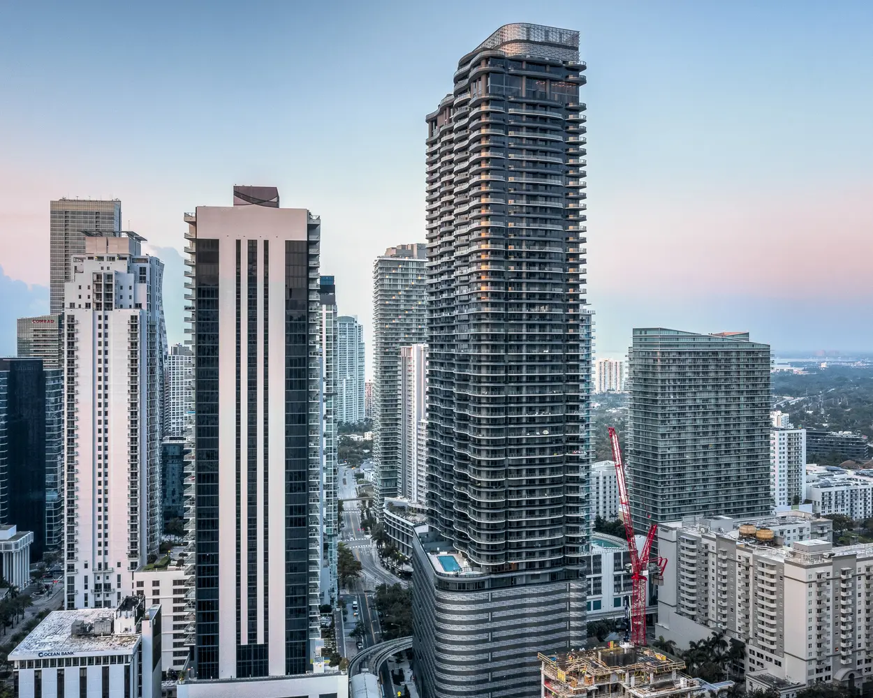 Brickell Flatiron tower among Miami skyline buildings at dusk.