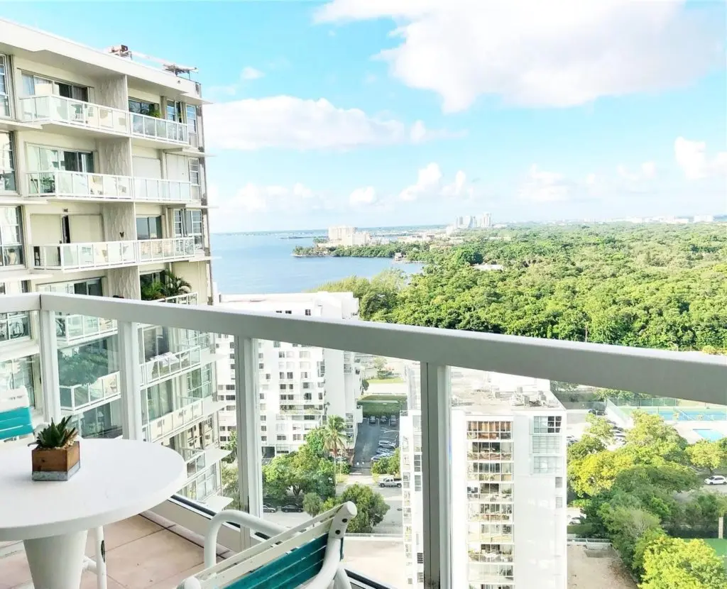 Brickell Townhouse balcony with bay view overlooking lush greenery.
