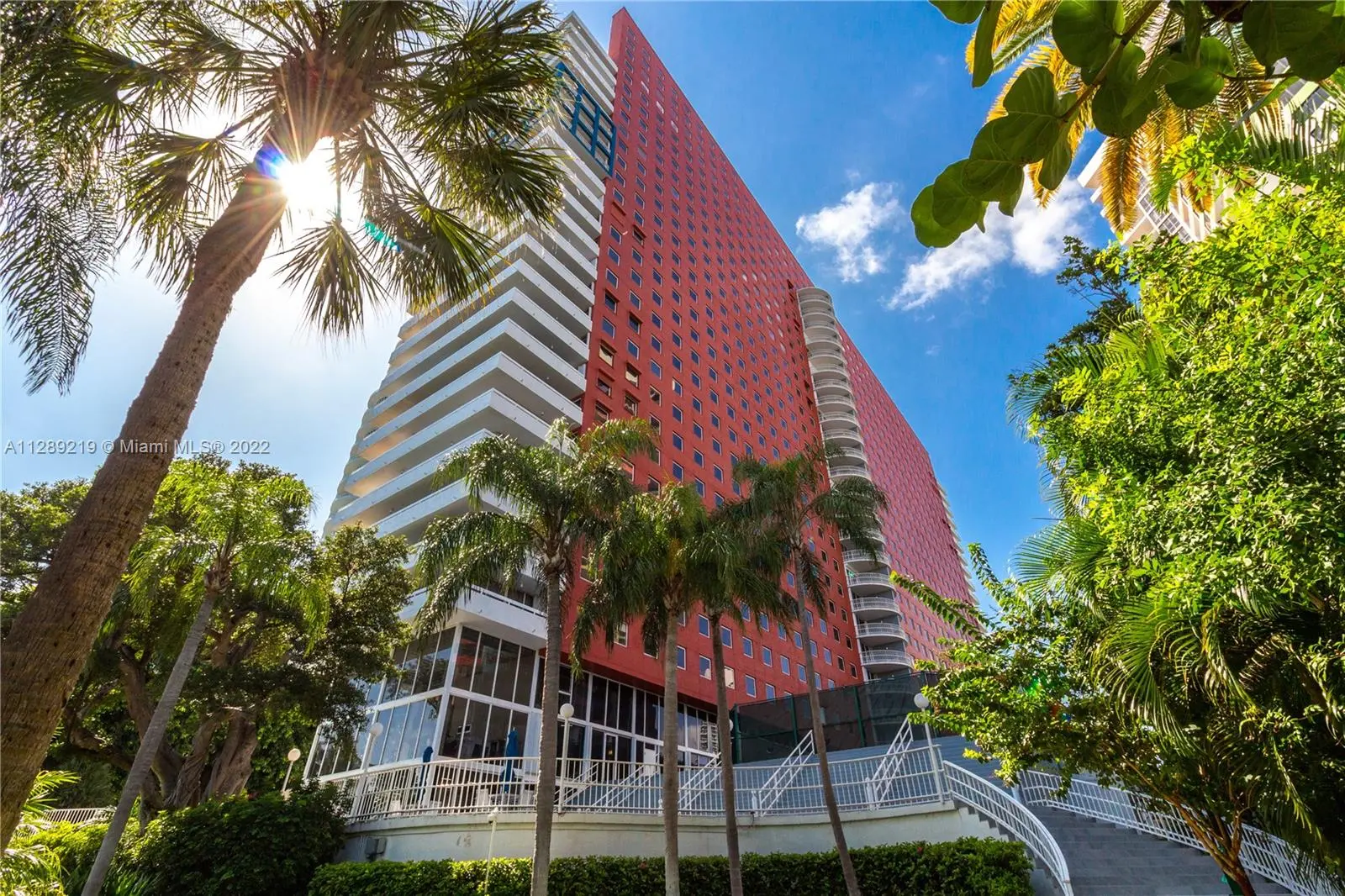 Imperial at Brickell's striking red facade framed by lush palm trees.