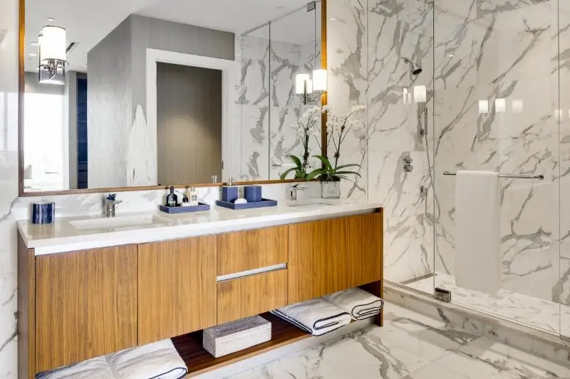 Miami Luxury features a modern bathroom with marble surfaces and wooden vanity.