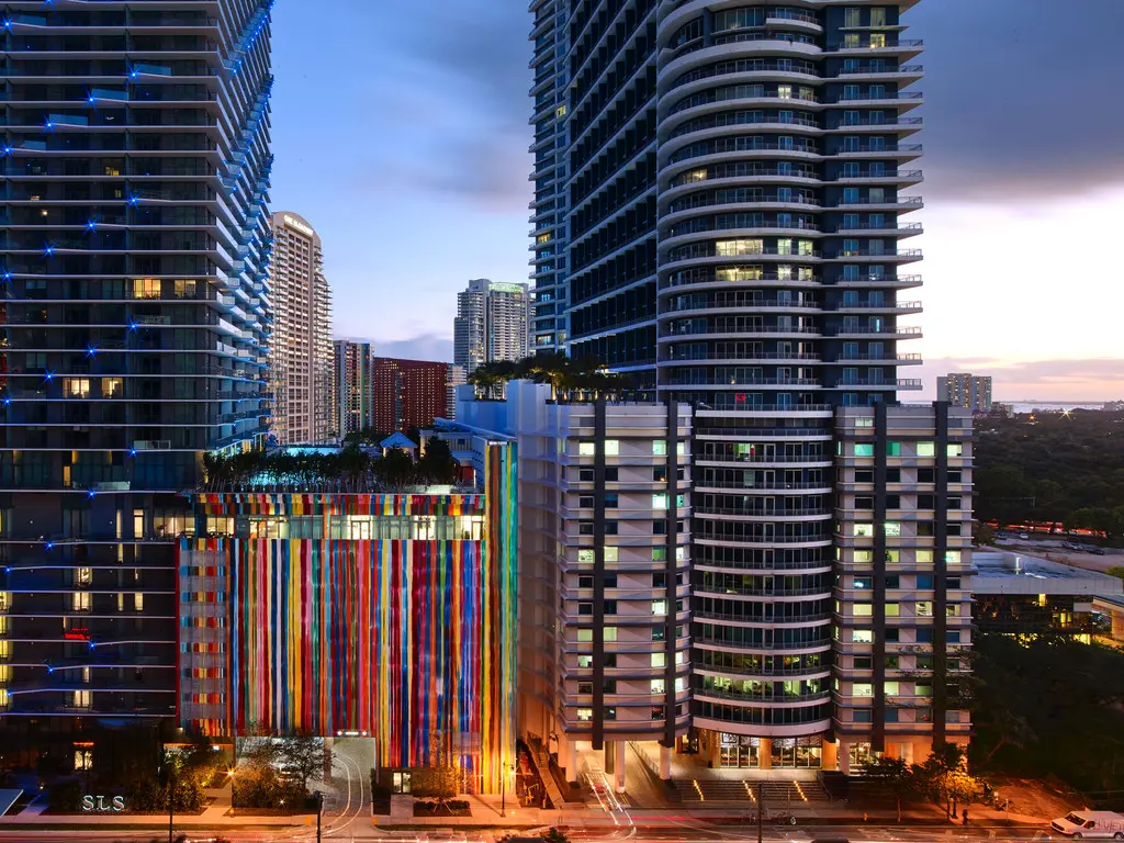 Colorful facade of SLS Brickell against Miami skyline at dusk.