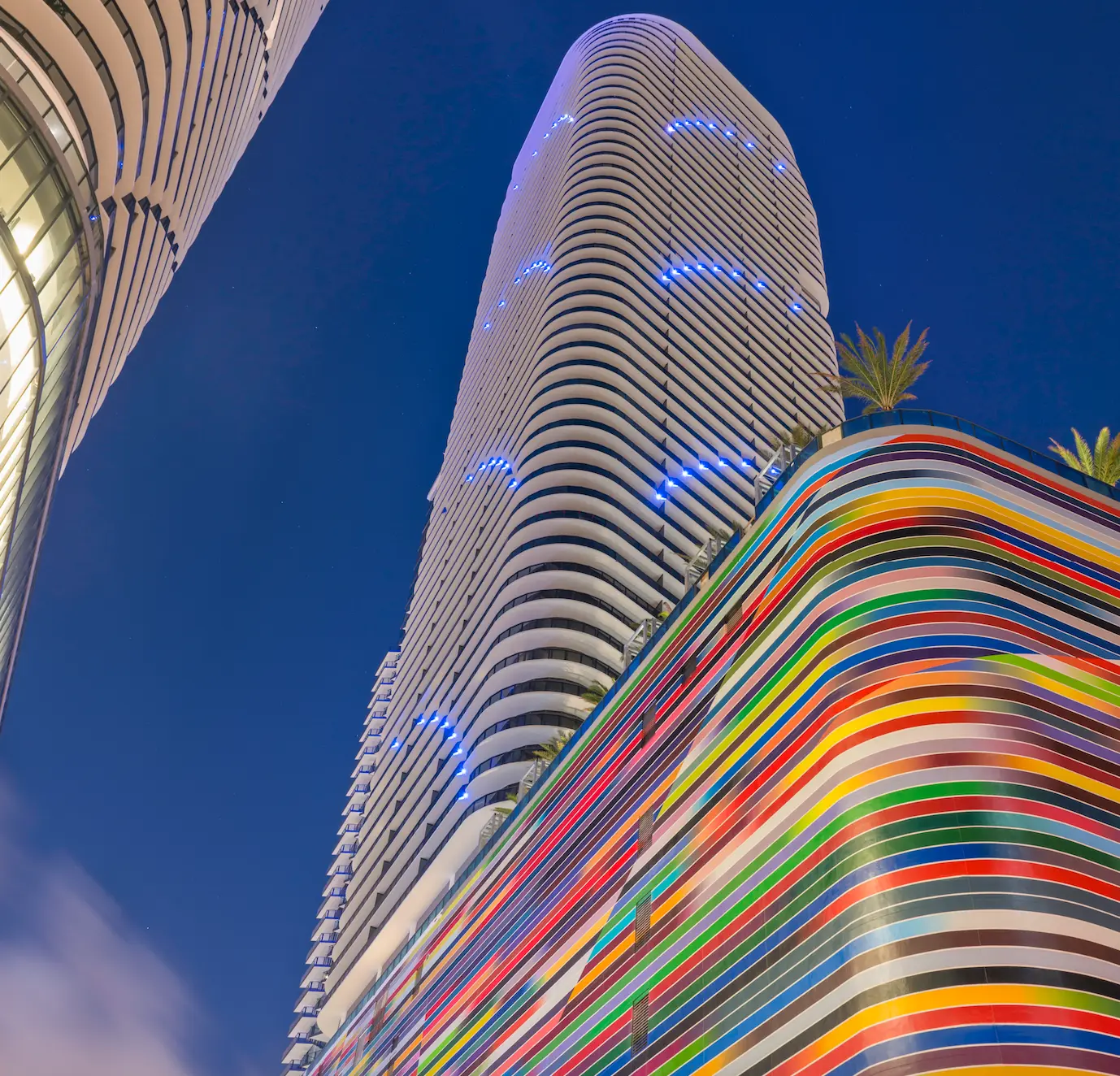 Night view of SLS Lux building's colorful striped exterior in Miami.