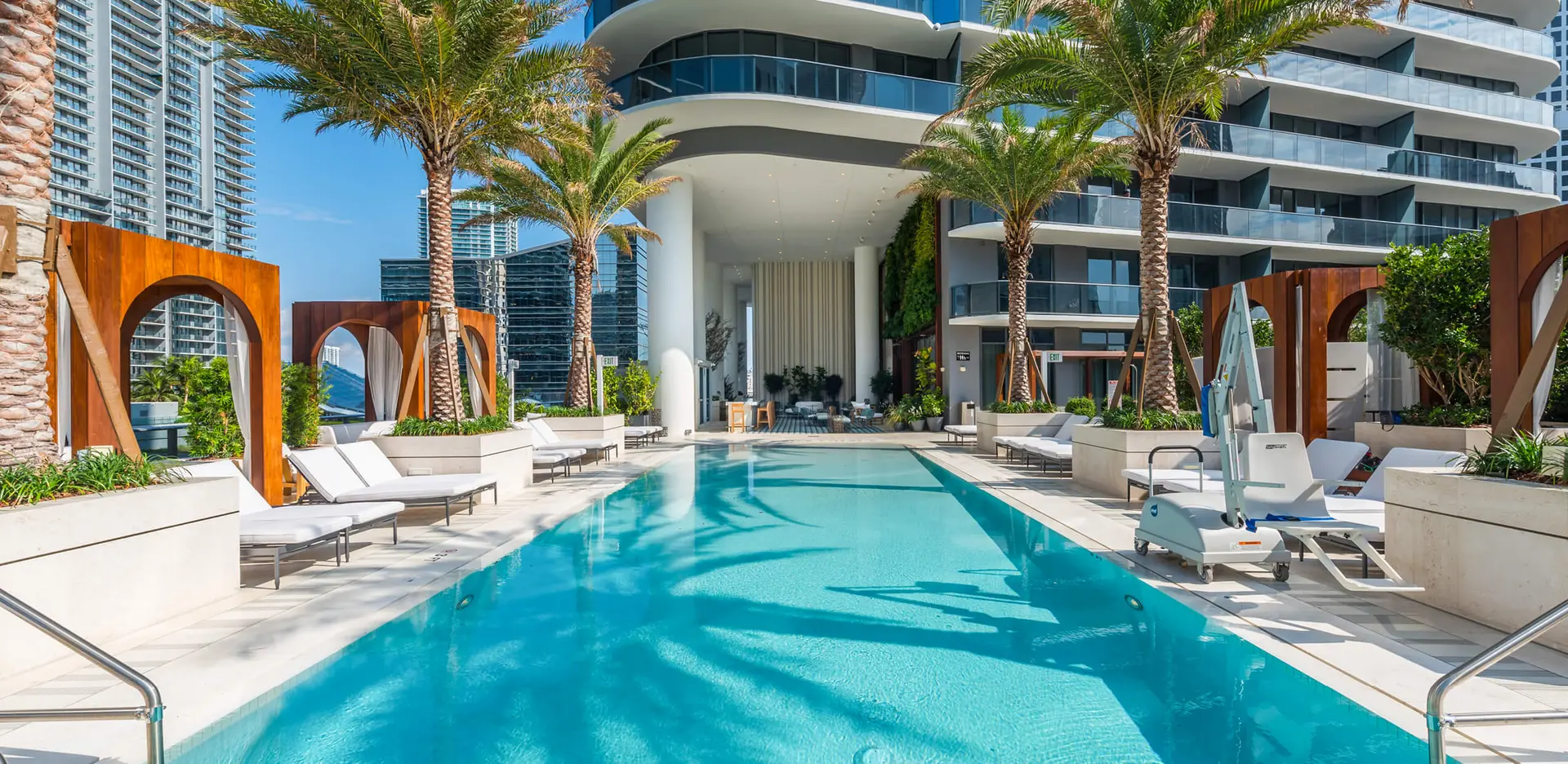The luxurious pool area at SLS Lux Miami with chic lounge chairs and palm trees.