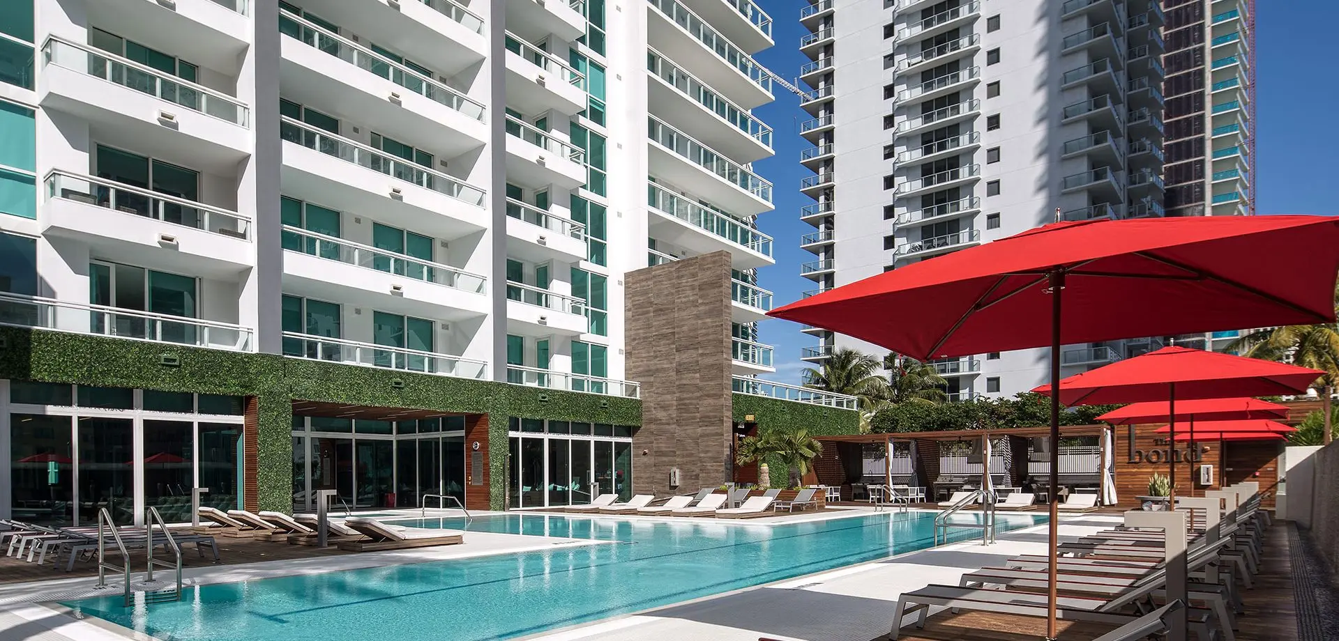 The Bond on Brickell pool area with red umbrellas and modern architecture.