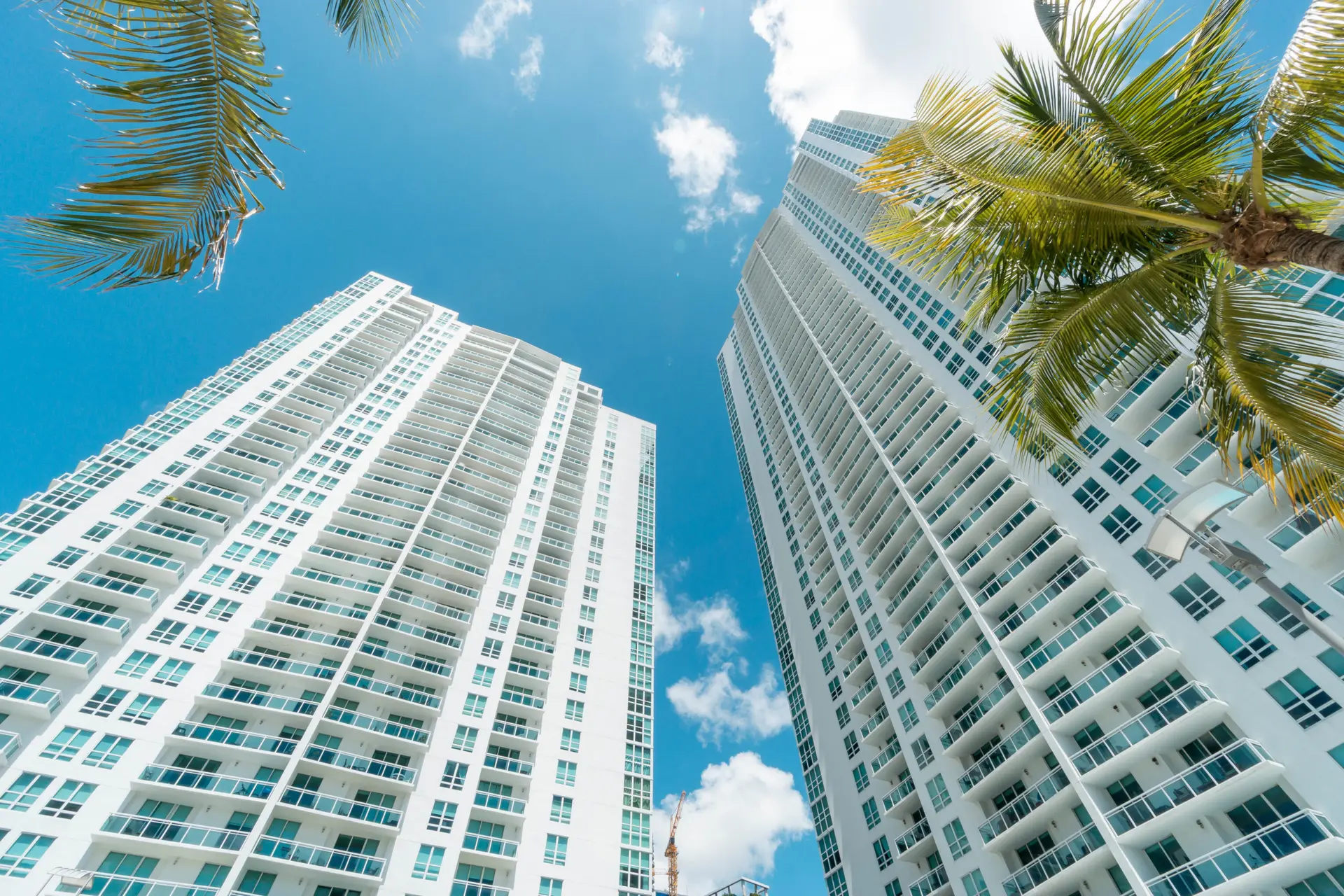 Two modern high-rise buildings of The Plaza on Brickell West against a blue sky.