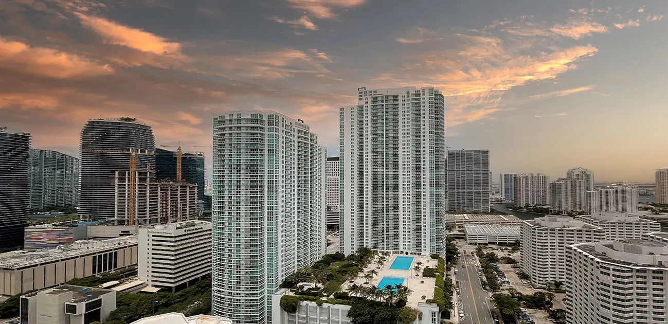 The Plaza on Brickell West towers with Miami skyline at sunset.