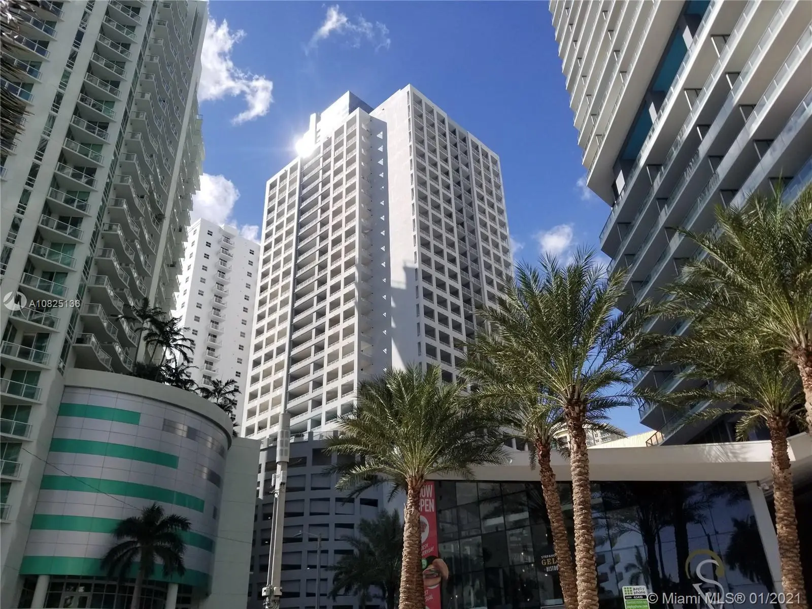 The Sail features tall modern buildings in Miami with palm trees and clear blue skies.
